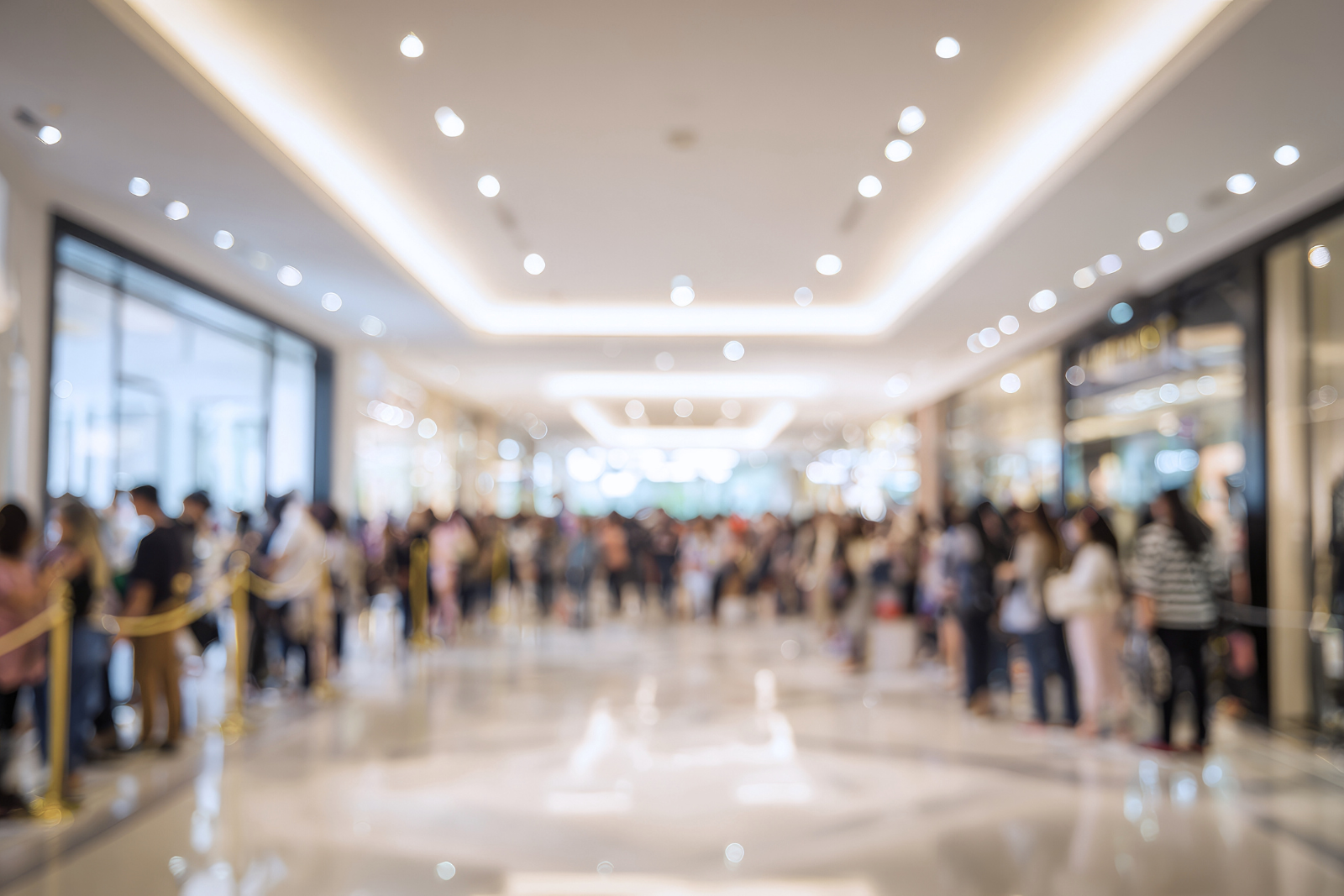 Imagem de shopping lotado com filas nas lojas, com efeito blur, representando barreira de vendas.